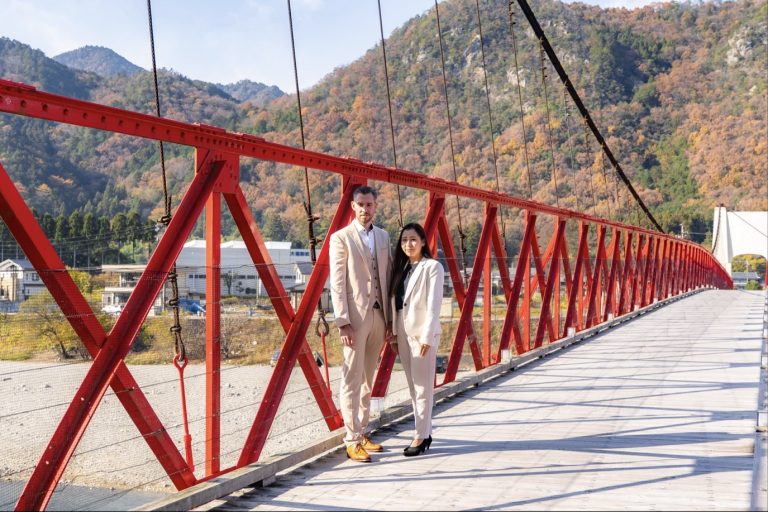 Erika and Norwin Sommerfeld walking and smiling on a red bridge in Japan – N&E Consulting team photo