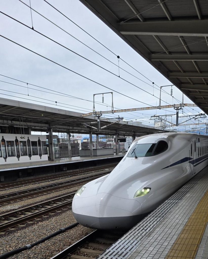 日本の駅に到着する新幹線。移動の利便性、人と人とのつながり、そして日本での暮らしと仕事を象徴する風景。